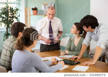 Senior teacher speaking with a group of young students Senior teacher speaking with a group of young students 142989379