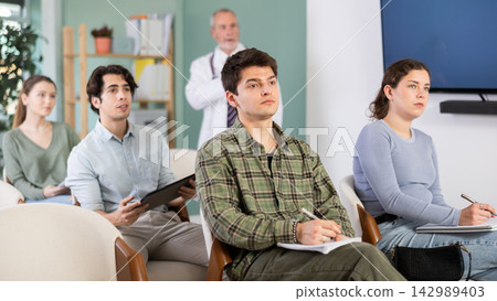 Students listen to lecture in classroom, with medical professor in background 142989403