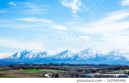 A magnificent autumn landscape of the hills in Biei, Hokkaido, with a blue sky and the snow-capped Tokachi Mountain Range. A magnificent autumn landscape of the hills in Biei, Hokkaido, with a blue sky and the snow-capped Tokachi Mountain Range. 142990466