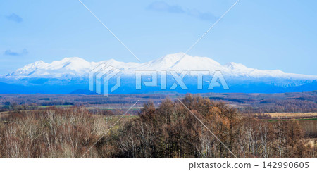 The magnificent scenery of the Daisetsuzan mountain range and Mount Asahidake viewed from the hills of Biei in autumn, against a clear blue sky. The magnificent scenery of the Daisetsuzan mountain range and Mount Asahidake viewed from the hills of Biei in autumn, against a clear blue sky. 142990605