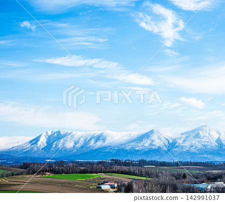 A magnificent view from the hills of Biei, Hokkaido, in autumn, with a blue sky and snow-capped Mount Tokachi. A magnificent view from the hills of Biei, Hokkaido, in autumn, with a blue sky and snow-capped Mount Tokachi. 142991037