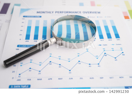 Magnifying glass on spreadsheet and graph paper. Magnifying glass on spreadsheet and graph paper. 142991230