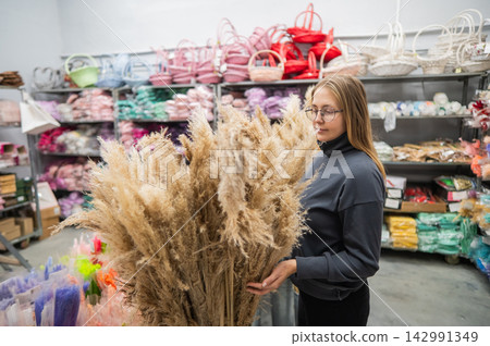 A Caucasian woman buys dried flowers at a home decor store. 142991349
