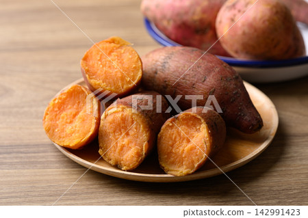 Steamed orange sweet potatoes on wooden plate ready to eat, healthy food Steamed orange sweet potatoes on wooden plate ready to eat, healthy food 142991423