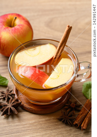 Fresh apple cider in a glass with cinnamon stick, star anise and sliced red appless Fresh apple cider in a glass with cinnamon stick, star anise and sliced red appless 142991447