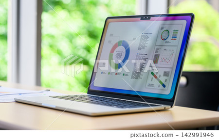Laptop on the desk, displaying pie charts and bar graphs. Laptop on the desk, displaying pie charts and bar graphs. 142991946