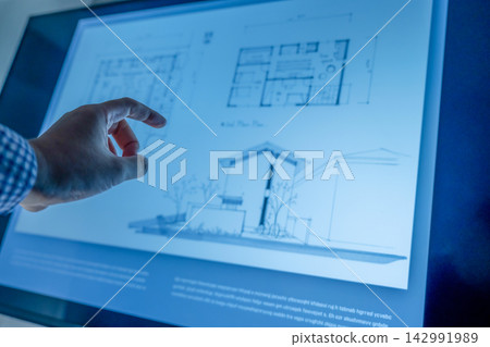 一隻手指向一張藍光下的建築圖。 142991989