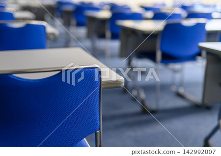 Focus on the blue chairs and white table in the conference room, and the chair in the foreground. Focus on the blue chairs and white table in the conference room, and the chair in the foreground. 142992007