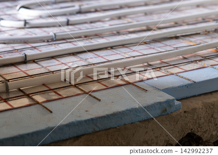 Professional installation of underfloor heating pipes in new home. Insulated tubing, modern construction methods and efficient indoor climate control. Professional installation of underfloor heating pipes in new home. Insulated tubing, modern construction methods and efficient indoor climate control. 142992237