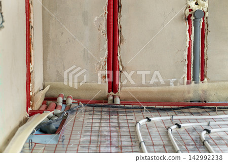 Radiant floor heating system with plastic pipes secured to insulation panels before concrete placement. Energy saving technology and residential construction. Radiant floor heating system with plastic pipes secured to insulation panels before concrete placement. Energy saving technology and residential construction. 142992238