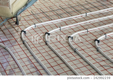Residential construction site with underfloor heating pipes installed before flooring. Thermal comfort, modern building systems and sustainable home technology. Residential construction site with underfloor heating pipes installed before flooring. Thermal comfort, modern building systems and sustainable home technology. 142992239