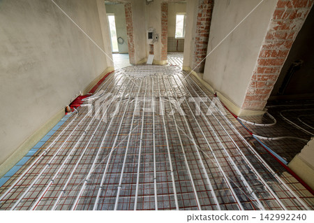 Radiant floor heating system with plastic pipes secured to insulation panels before concrete placement. Energy saving technology and residential construction. Radiant floor heating system with plastic pipes secured to insulation panels before concrete placement. Energy saving technology and residential construction. 142992240