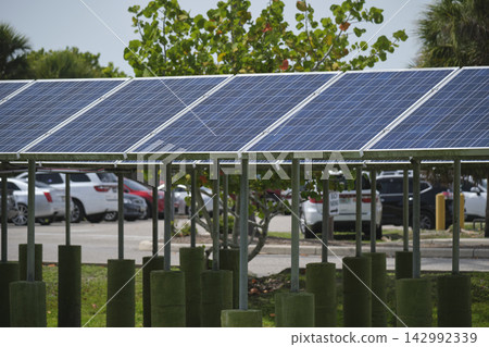 Solar panels installed on stand frame near parking lot for effective generation of clean electricity. Photovoltaic technology integrated in urban infrastructure for electric car charging Solar panels installed on stand frame near parking lot for effective generation of clean electricity. Photovoltaic technology integrated in urban infrastructure for electric car charging 142992339