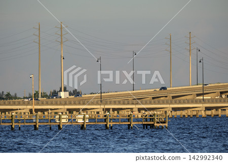 Barron Collier Bridge and Gilchrist Bridge in Florida with moving traffic. Transportation infrastructure in Charlotte County connecting Punta Gorda and Port Charlotte over Peace River Barron Collier Bridge and Gilchrist Bridge in Florida with moving traffic. Transportation infrastructure in Charlotte County connecting Punta Gorda and Port Charlotte over Peace River 142992340