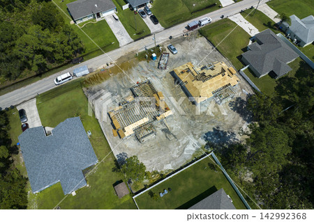 Professional builders working on roof construction of unfinished suburban home with wooden frame structure in Florida rural area. Concept of housing development in America 142992368