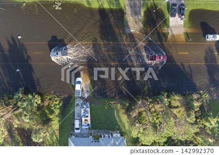 Aerial view of flooded street after hurricane rainfall with driving cars in Florida residential area. Consequences of natural disaster Aerial view of flooded street after hurricane rainfall with driving cars in Florida residential area. Consequences of natural disaster 142992370