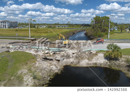 Reconstruction of damaged road bridge destroyed by river after flood water washed away asphalt. Rebuilding of ruined transportation infrastructure 142992388
