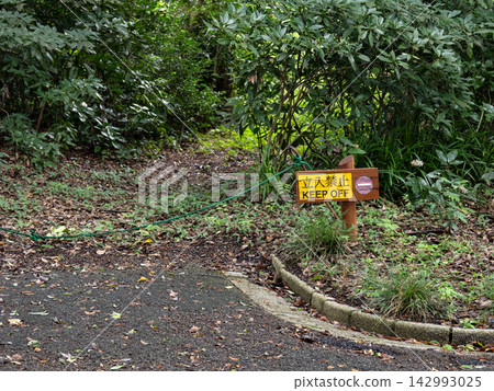 A rope and sign indicating that entry from the park's designated paths to the unpaved road is prohibited. A rope and sign indicating that entry from the park's designated paths to the unpaved road is prohibited. 142993025