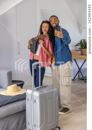 Couple posing for selfie with man holding phone and woman holding passport near suitcase in attic Couple posing for selfie with man holding phone and woman holding passport near suitcase in attic 142993445