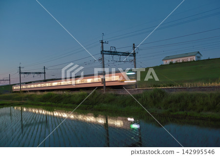 夜幕降臨,駛過的當地列車倒映在水稻田中。 夜幕降臨,駛過的當地列車倒映在水稻田中。 142995546