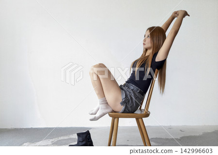 一位女士坐在簡約風格的工作室的椅子上伸展身體。 一位女士坐在簡約風格的工作室的椅子上伸展身體。 142996603