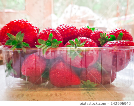Fresh red strawberries in plastic container on table Fresh red strawberries in plastic container on table 142996943