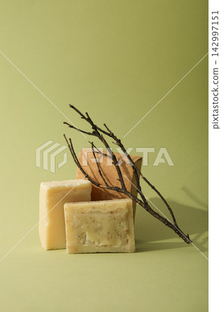 Two soap bars and a twig arranged on a green surface Two soap bars and a twig arranged on a green surface 142997151