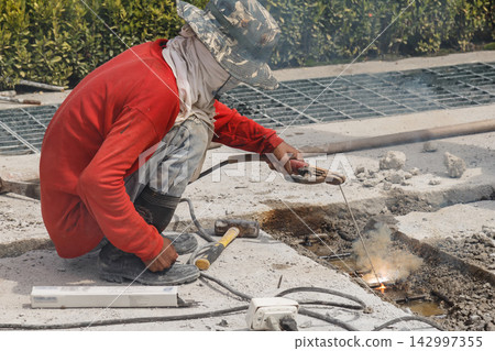 Construction Worker Welding Concrete Road Repair on Outdoor Site Construction Worker Welding Concrete Road Repair on Outdoor Site 142997355