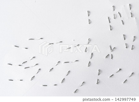 Staples pushed into a paper, metal office staple needles Staples pushed into a paper, metal office staple needles 142997749