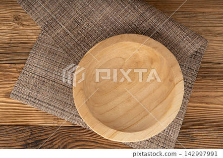 Empty wood bowl on table, plate on wooden table and tablecloth, light rustic dish mockup Empty wood bowl on table, plate on wooden table and tablecloth, light rustic dish mockup 142997991