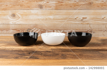 Three empty bowls on table, white porcelain, black and dishes on tabletop, rustic dish Three empty bowls on table, white porcelain, black and dishes on tabletop, rustic dish 142998001