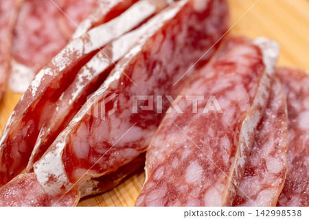 Sliced fuet sausage on wooden board closeup Sliced fuet sausage on wooden board closeup 142998538