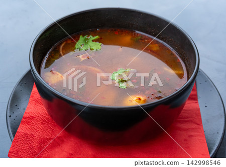 Tom yum thai soup with chicken in black bowl Tom yum thai soup with chicken in black bowl 142998546