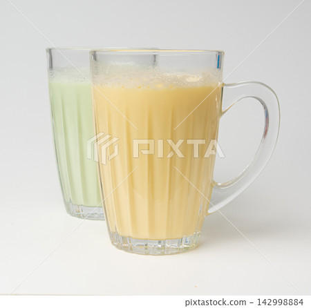 Vanilla milk shake in glass. Milkshake on yellow background, white whey protein smoothie Vanilla milk shake in glass. Milkshake on yellow background, white whey protein smoothie 142998884
