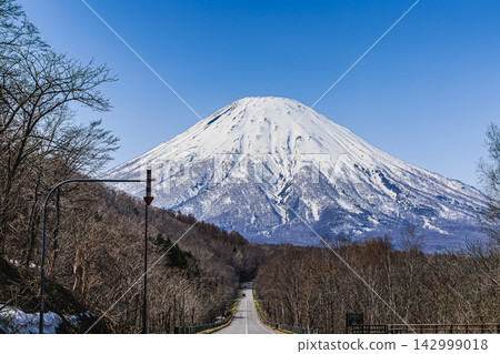 一條筆直的道路延伸至白雪皚皚的羊蹄山,展現了北海道壯麗的自然風光。 一條筆直的道路延伸至白雪皚皚的羊蹄山,展現了北海道壯麗的自然風光。 142999018