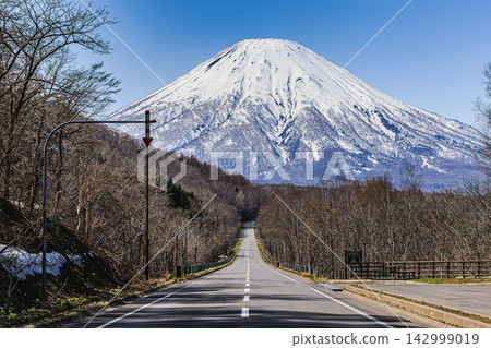 北海道駕車景象:羊蹄山依然白雪皚皚,巍峨聳立在藍天之下,一條筆直的道路在你面前延伸開來。 北海道駕車景象:羊蹄山依然白雪皚皚,巍峨聳立在藍天之下,一條筆直的道路在你面前延伸開來。 142999019