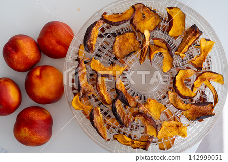 Dried nectarines and peaches in fruit dryer close up 142999051