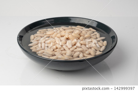 Soaked white beans, legume seeds in water 142999397