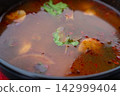 Tom yum thai soup with chicken in black bowl 142999404