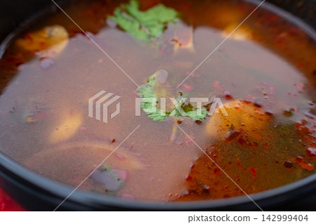 Tom yum thai soup with chicken in black bowl 142999404