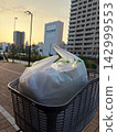 黃昏時分，城市背景下，自行車籃裡的購物袋輕輕搖曳。 142999553
