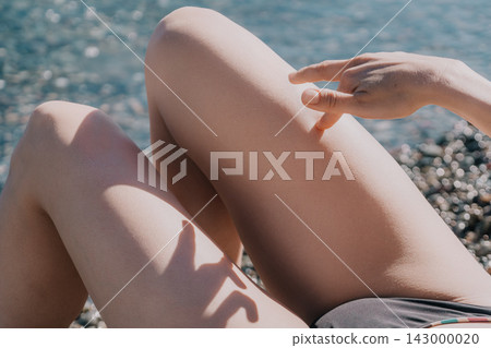 Legs hand beach relaxing on a rocky shore during summer sunlight representing wellness and carefree vacation moments for travel concepts Legs hand beach relaxing on a rocky shore during summer sunlight representing wellness and carefree vacation moments for travel concepts 143000020