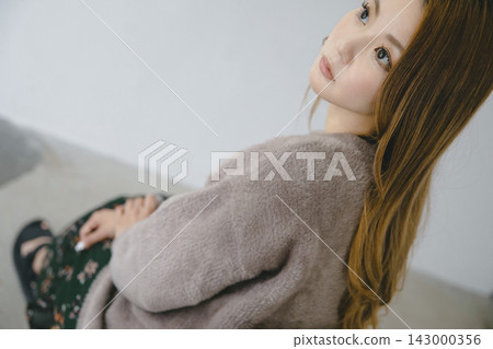 秋冬季節,一位美麗的日本女性穿著碎花連身裙,在室內拍攝的背影照。 秋冬季節,一位美麗的日本女性穿著碎花連身裙,在室內拍攝的背影照。 143000356