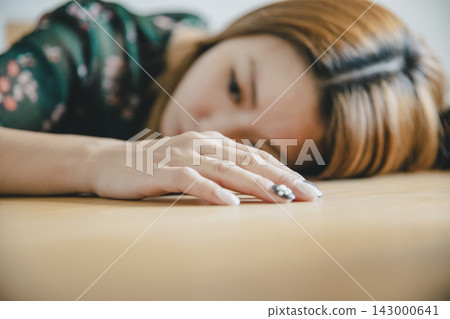 A beautiful Japanese woman relaxes with her cheek resting on the dining table. A beautiful Japanese woman relaxes with her cheek resting on the dining table. 143000641