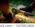 Man in protective gloves cutting metal with an angle grinder outdoors, bright sparks flying. Concept of manual labour, home workshop, DIY metalwork and work safety. 143001866