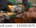 Man in protective gloves cutting metal with an angle grinder outdoors, bright sparks flying. Concept of manual labour, home workshop, DIY metalwork and work safety. 143001870