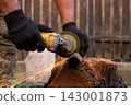 Man in protective gloves cutting metal with an angle grinder outdoors, bright sparks flying. Concept of manual labour, home workshop, DIY metalwork and work safety. 143001873