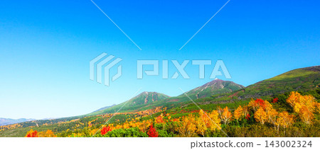 The Tokachi Mountain Range in autumn colors, viewed from the Bogakudai observation deck in Biei Town, Hokkaido, under a clear blue sky. 143002324