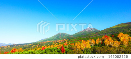 The Tokachi Mountain Range in autumn colors, viewed from the Bogakudai observation deck in Biei Town, Hokkaido, under a clear blue sky. 143002326