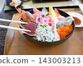 A luxurious seafood bowl topped with shrimp, sashimi, and whitebait. 143003213